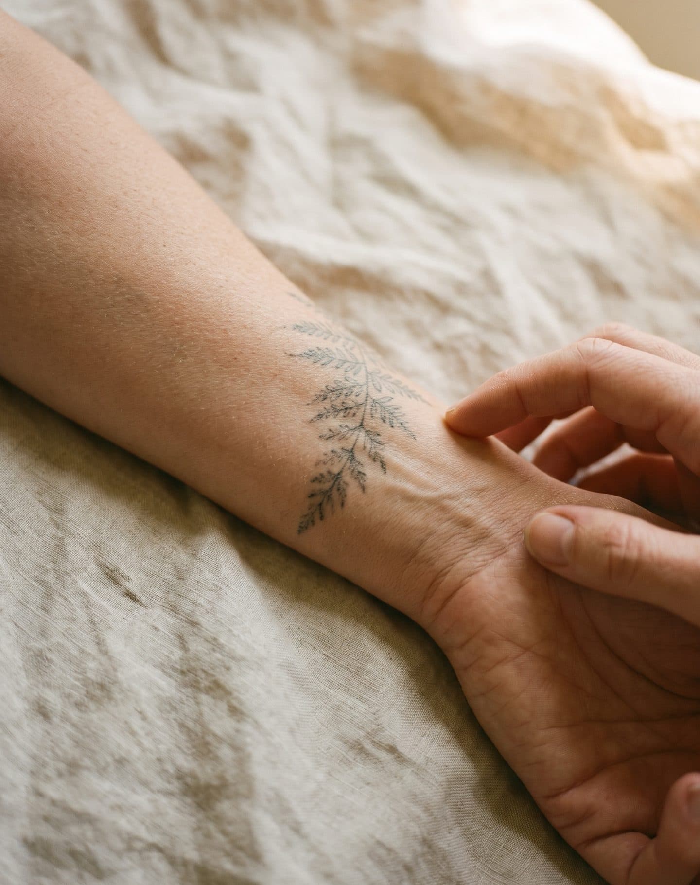 Innenseite eines Unterarms auf Leinen mit einem kleinen, bereits verblassten Tattoo aus feinen Linien